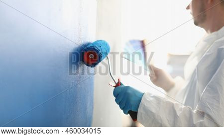 Painting White Wall With Blue Roller. Services Of Master Painter For Home Repair