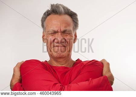 Mature Man 60plus Doing A Bear Hug To Stretch Out His Upper Back And Neck Muscles For Pain Relief