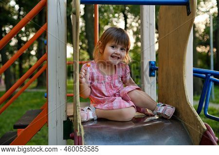 Cute Baby Girl Playing At Playground In Summer Sunny Day. Little Girl Licking Chupa Chups
