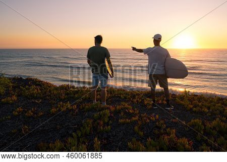 Surfers Watching The Waves At Sunset