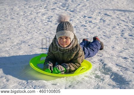 Boy Sliding Down The Hill On Saucer Sleds Outdoors, Winter Day, Ride Down The Hills, Winter Games An
