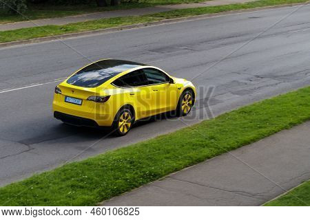 A Yellow Electric Car Is Driving Down The Street. Yellow Tesla Model X. Riga, Latvia - 15 Aug 2022.