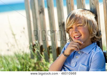 Cute Boy Relaxing Next To Wooden Fence.