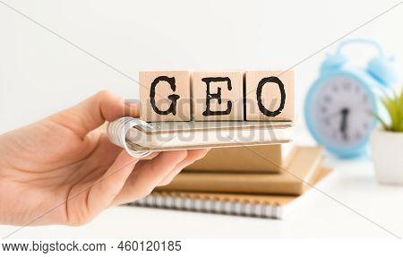 The Hand Puts The Cube Block With The Inscription Geo.