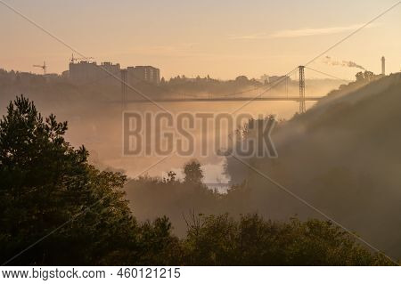 Scenic Sunrise In Zhytomyr City. Morning Fog Over Valley Of Teteriv River. High Pedestrian Cable Bri