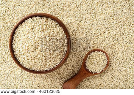 Raw Sesame Seeds In A Wooden Bowl And Spoon Over White Til Background. Organic Benne Grains For Heal