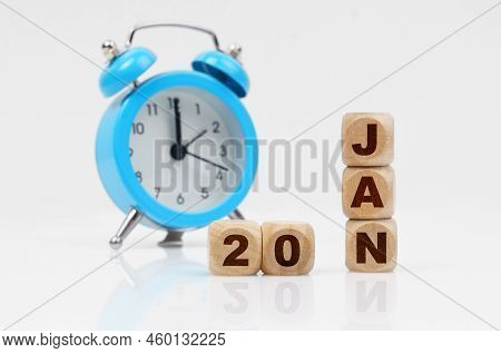 20st Of January. Wooden Cube Calendar For January 20, Next To A Blue Alarm Clock. Objects On A Refle