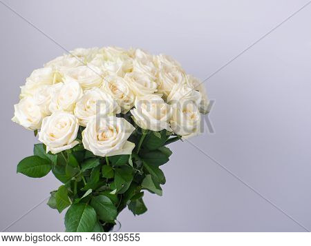 Beautiful Bouquet Of White Blooming Roses In Glass Vase On The White Wall Background. White Flowers,