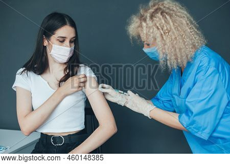 Female Doctor Administrating Covid-19 Vaccine To A Caucasian Patient At The Hospital. Irus, Epidemic