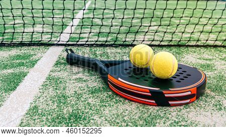 Yellow Balsl On Top Of The Padel Racket And Behind Net On Green Court Grass Turf
