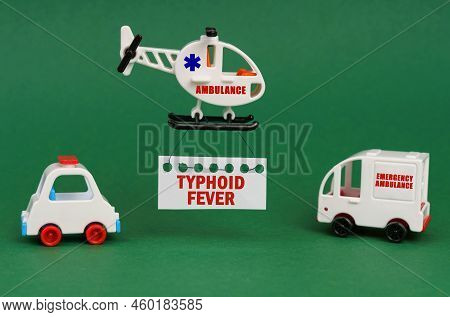 Medical Concept. On A Green Surface, Cars And An Ambulance Helicopter With A Sign - Typhoid Fever