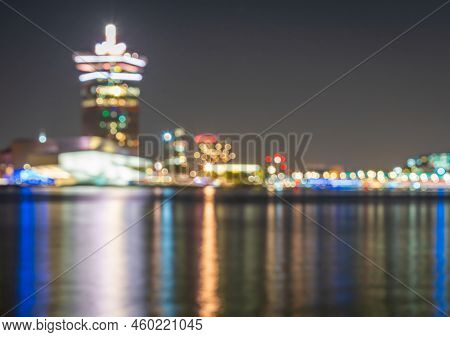 Defocused Skyline Of Amsterdam At Night, Blurred Lights Of Traffic And Modern Buildings Around Ij Ri