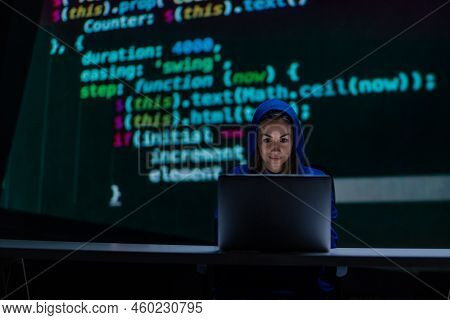 Hooded Anonymous Hacker Woman By Computer In The Dark Room At Night, Cyberwar Concept.