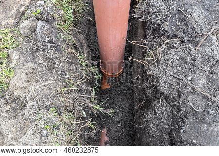 An Orange Plastic Pipe From A Septic Tank With A Diameter Of 160 Mm Lying In A Ditch.