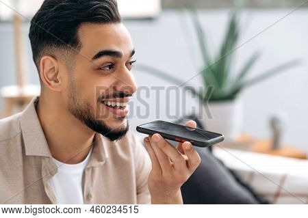 Speakerphone Conversation. Close-up Of Excited Positive Indian Or Arabian Man, Sitting On A Sofa In 