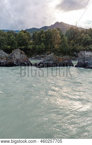 A Fast-flowing Wide And Full-flowing Mountain River. Large Rocks Stick Out Of The Water. Big Mountai