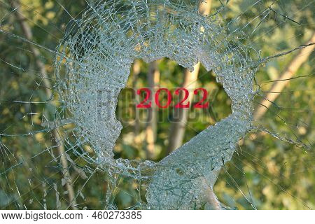Hard And Tragic 2022 Year. War. A Hole In The Glass Or Window. Broken Window Overlooking The Green F