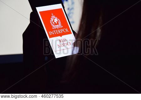 Person Holding Smartphone With Interpol Logo Displayed On Screen.