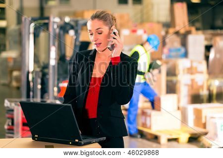 Amichevole donna, dispatcher o supervisore tramite cellulare e computer portatile al magazzino di inoltro comp