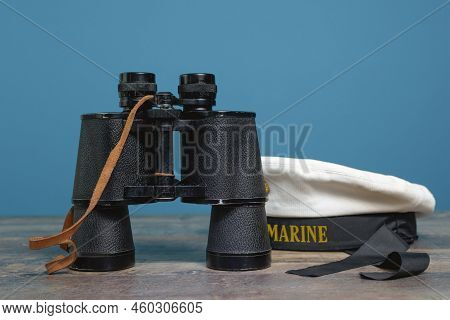 Ship Binoculars And Peakless Cap On A Turquoise Background On A Textured Wooden Table