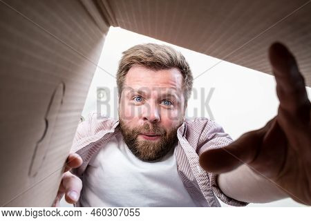 Satisfied Man Holds Out His Hand, Trying To Get A Gift Or Parcel From Unpacked Box. Unboxing Inside 