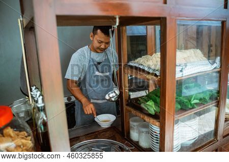 Man Seller In Apron Stir The In The Bowl