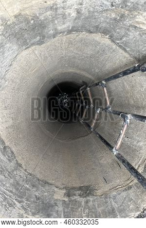 Deep Concrete Well, Water At The Bottom Of The Well, Stairs Down The Well. High Quality Photo