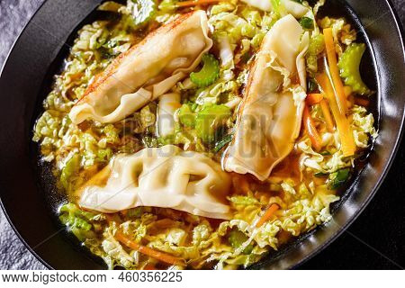 Close-up Of Asian Potsticker Gyoza Soup With Dumpling Of Ground Chicken, Napa Cabbage, Scallions, Gi