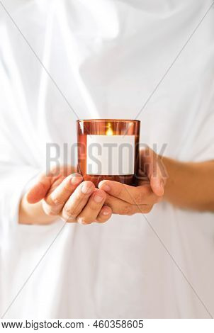 Woman In White Clothing Holding Burning Candle Close-up. Church Poster. Mock Up For Candle Shop. Spa