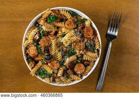 Rotini Pasta Served With Italian Sausage And Sauteed Spinach.