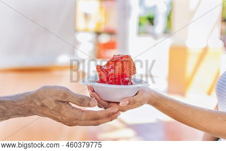 Two Hands Sharing A Shaved Ice In The Street. Close Up Of Two Hands Sharing A Cup Of Shaved Ice On T
