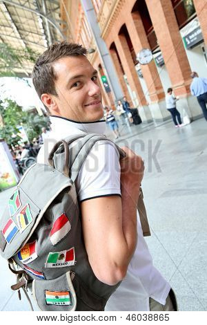 Turista sonriente con la mochila en la estación de tren