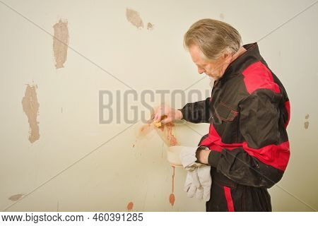 Older Man Working In Empty Apartment Cleaning Dirty Walls