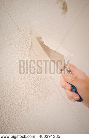 Older Man Removing Old Wallpapers Off The Walls In Empty Apartment