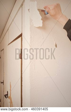 Older Man Removing Old Wallpapers Off The Walls In Empty Apartment