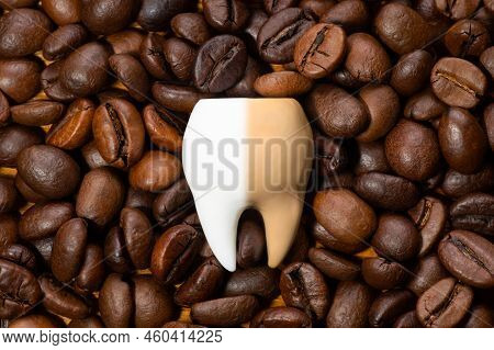 Large Half-white And Half-brown Tooth On A Pile Of Roasted Coffee Beans. Coffee Staining And Teeth W