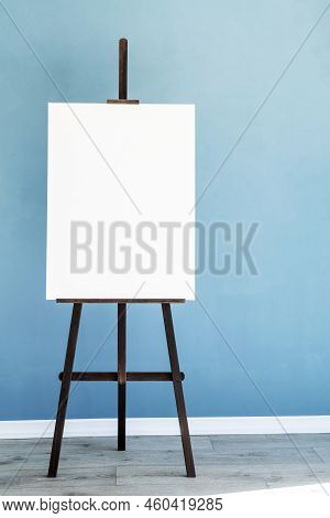Wooden Easel With Blank Canvas On Light Blue Background For Mockup Design