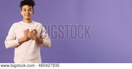 Portrait Of Romantic Handsome Hispanic Man With Dreads, Hold Hands Pressed To Heart And Smiling Plea
