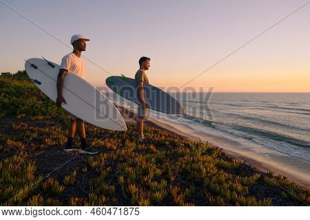Surfers Watching The Waves At Sunset