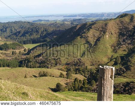 Fore Ground Rustic Post And Rural Farmland And View Down Valley To Coast On West Coast North Island 