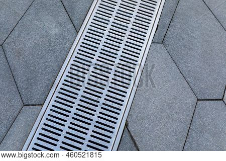 Metal Storm Sewer Grate On Shaped Paving Slabs In Park. Drainage Systems On Paving Slabs. Sidewalk C