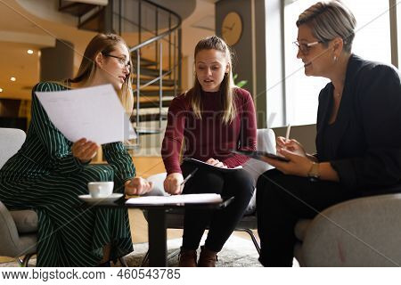 Low Angle View Of Caucasian Female Coworkers Discussing Project Reports And Brainstorming In Meeting