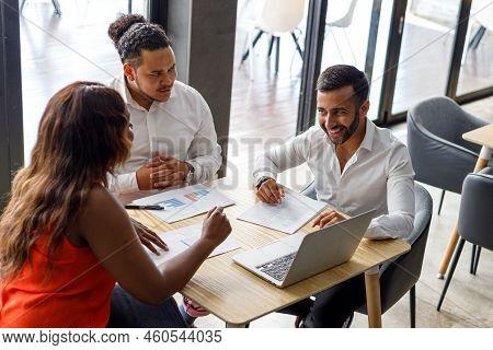 High Angle View Of Multiracial Coworkers Discussing Financial Data And Marketing Growth Report At De