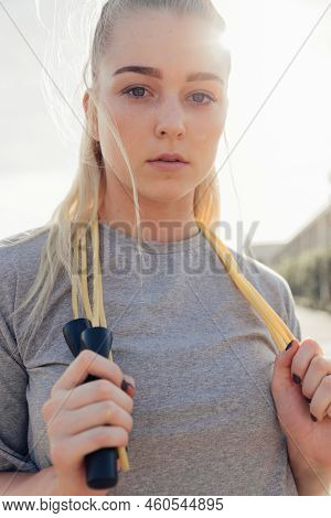 Close-up Portrait Of Serious Beautiful Young Woman Holding Jumping Rope While Exercising Against Cle