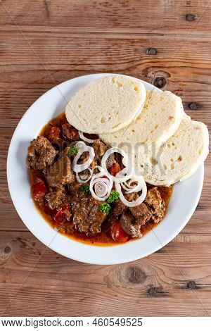 Czech Traditional Goulash With Breaded Dumpling And Onion On White Plate On Wooden Table