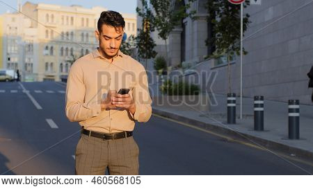 Stylish Bearded Hispanic Businessman Stand In City Center Street Uses Mobile Phone Texting Scrolling