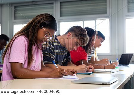 African American Teen High School Student Writing In Class. Group Of College Students Taking Notes I