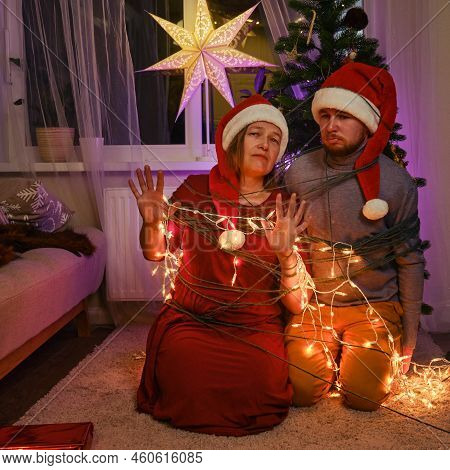 Entangled And Binding Family At The Christmas Tree In The Night Light Garlands. Unfree Parents On Ne