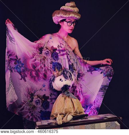 Happy Woman In Funny Wigs Give A Performance On A Studio Black Background. Smiling Woman Showing A H