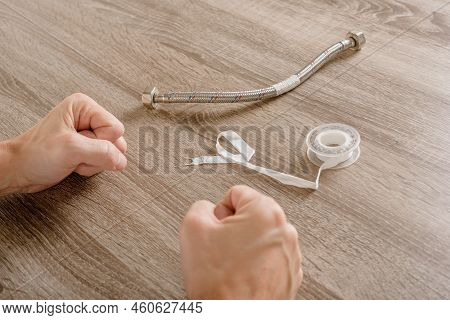 Male Technician Sitting In Front Of Connecting Water Pipe And Fum Tape